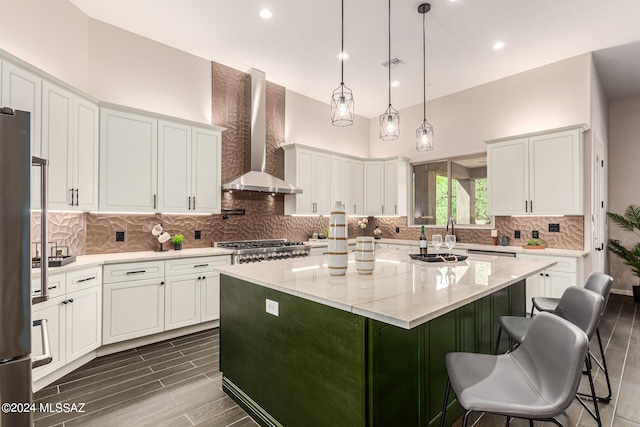 kitchen featuring a kitchen island, white cabinets, and wall chimney exhaust hood