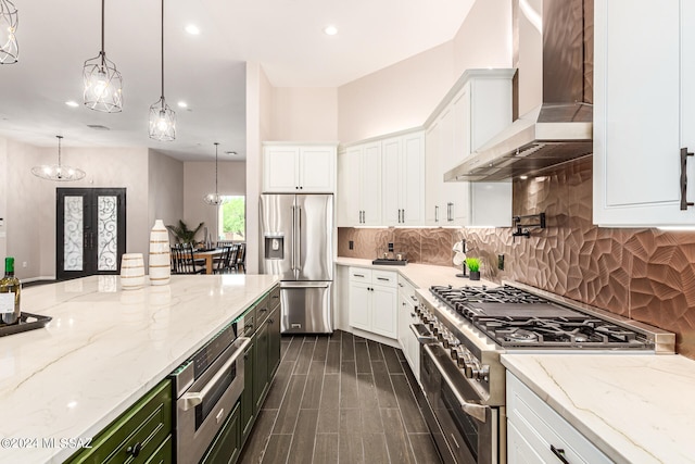 kitchen with white cabinetry, wall chimney exhaust hood, hanging light fixtures, and premium appliances