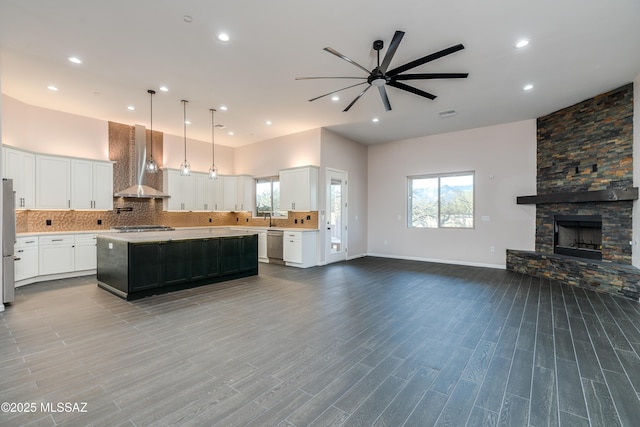 2102 N Corte El Rancho Merlita, Tucson, AZ 85715 - kitchen with wall chimney range hood, stainless steel appliances, open floor plan, ceiling fan, and a center island