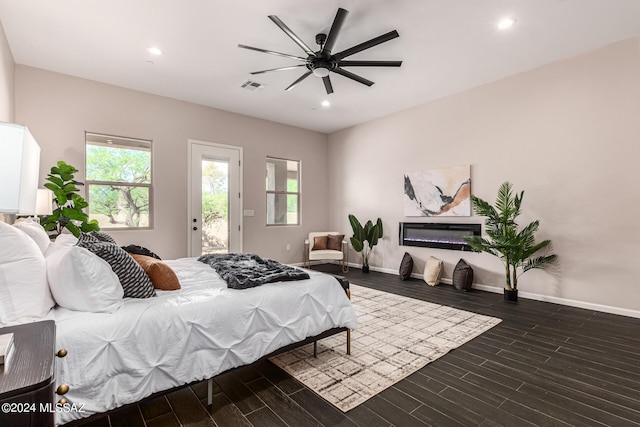 bedroom featuring multiple windows, access to exterior, dark wood-type flooring, and ceiling fan