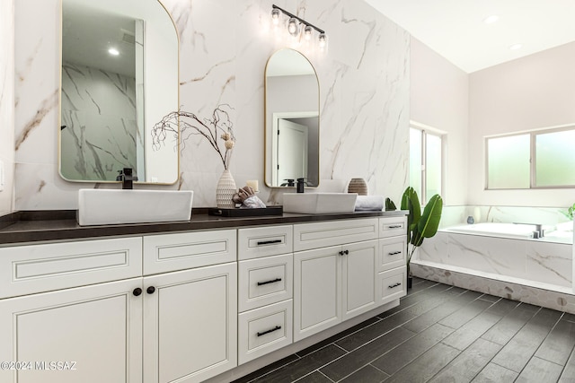 bathroom with vanity, tiled tub, and hardwood / wood-style flooring