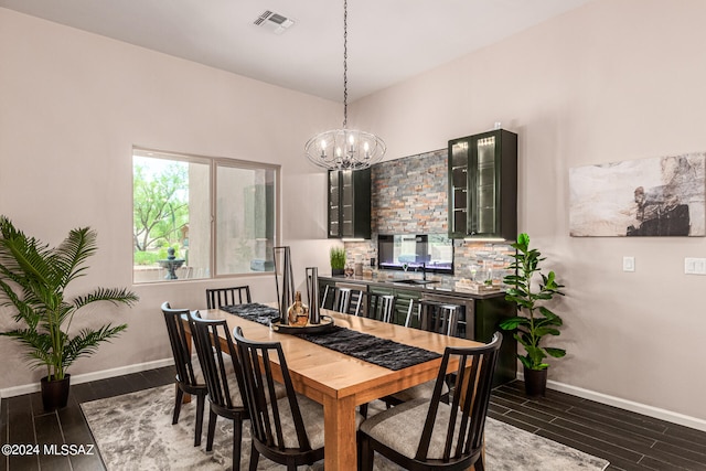 dining area with dark wood-type flooring and an inviting chandelier