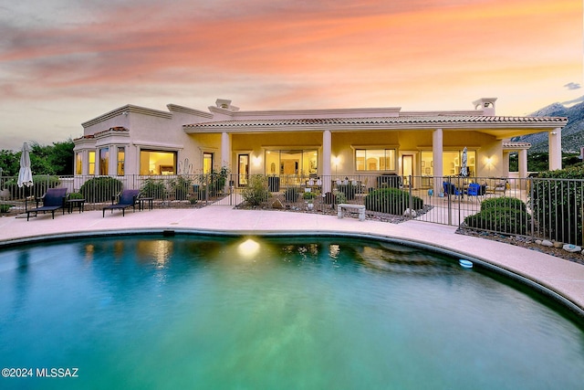 pool at dusk with a patio area