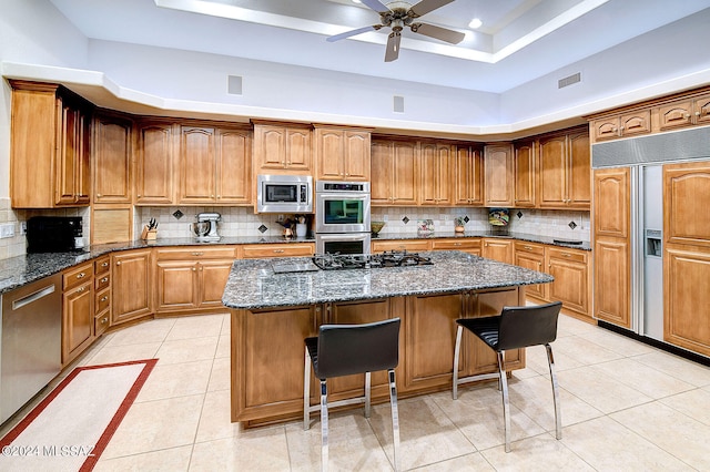 kitchen with built in appliances, a kitchen breakfast bar, a center island, and dark stone counters