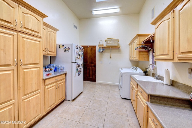 clothes washing area featuring light tile patterned flooring, cabinets, washer and clothes dryer, and sink