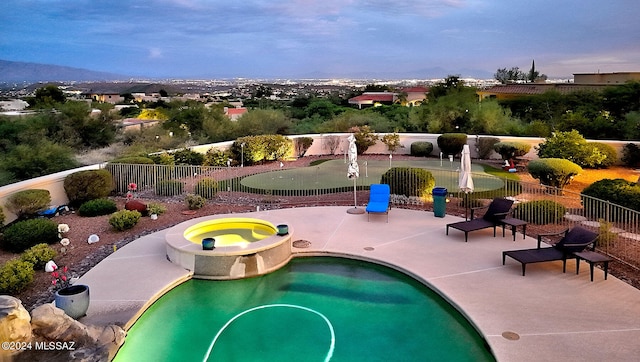 pool at dusk with an in ground hot tub