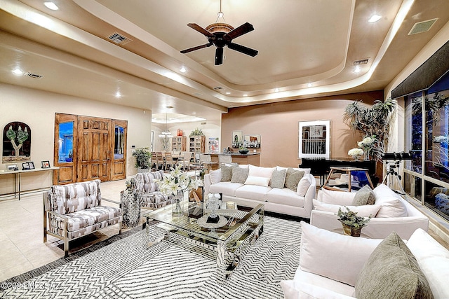 tiled living room with a tray ceiling and ceiling fan