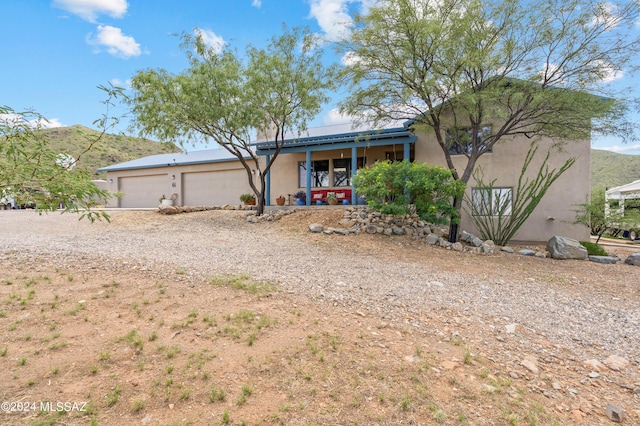 view of front facade with covered porch, a mountain view, an attached garage, and stucco siding