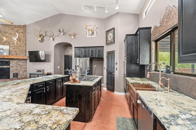 kitchen with arched walkways, stainless steel appliances, a kitchen island, and light stone countertops