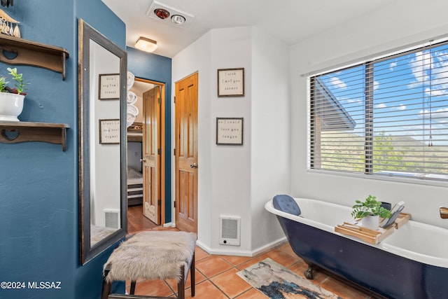 bathroom with a freestanding tub, visible vents, and tile patterned floors