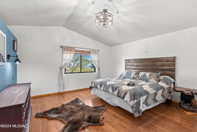 bedroom featuring lofted ceiling, wood finished floors, and baseboards