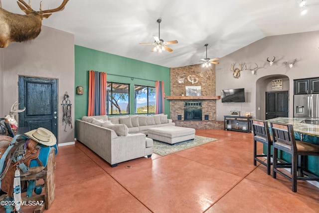 living room with arched walkways, ceiling fan, concrete flooring, a fireplace, and baseboards