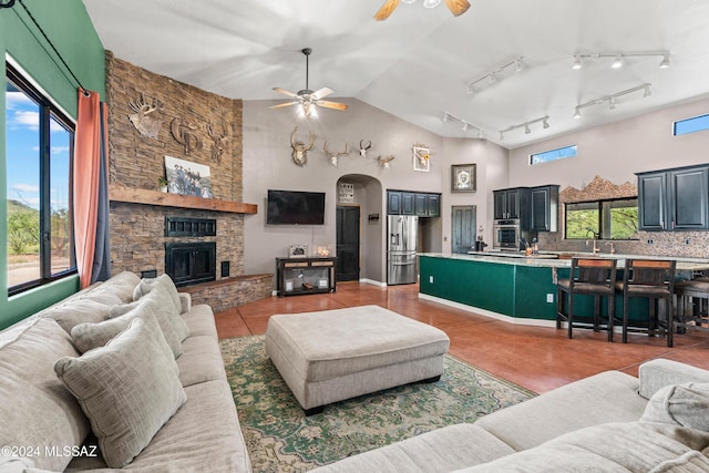 living room with a wealth of natural light, arched walkways, a fireplace, and high vaulted ceiling