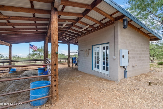 view of side of home with concrete block siding, an outdoor structure, an exterior structure, and french doors