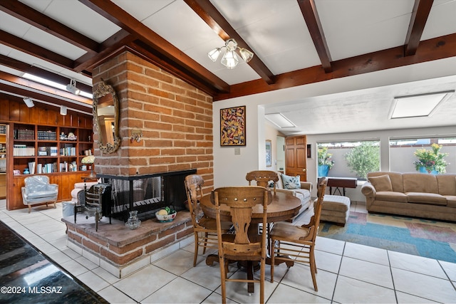 dining room with lofted ceiling with beams, a brick fireplace, and light tile patterned floors