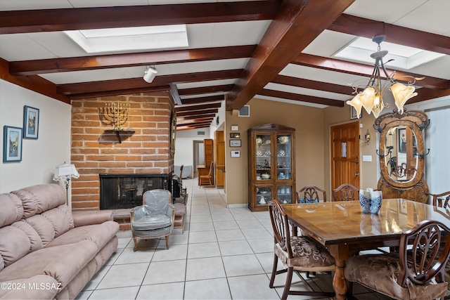 tiled dining area featuring lofted ceiling with skylight, a chandelier, and a brick fireplace