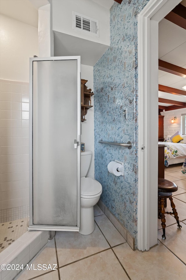 bathroom featuring tile patterned flooring, a shower with door, and toilet