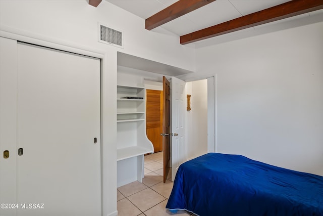 bedroom featuring beamed ceiling and light tile patterned floors