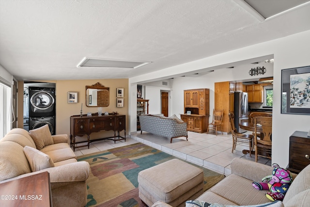 tiled living room featuring a textured ceiling and stacked washer / dryer