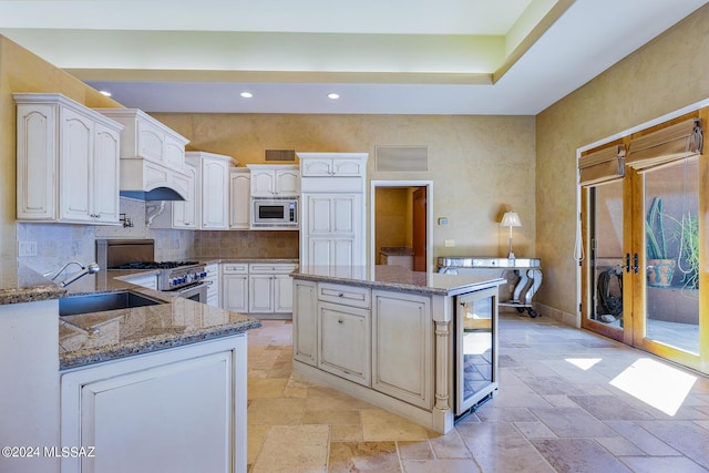 kitchen with wine cooler, appliances with stainless steel finishes, stone counters, sink, and tasteful backsplash