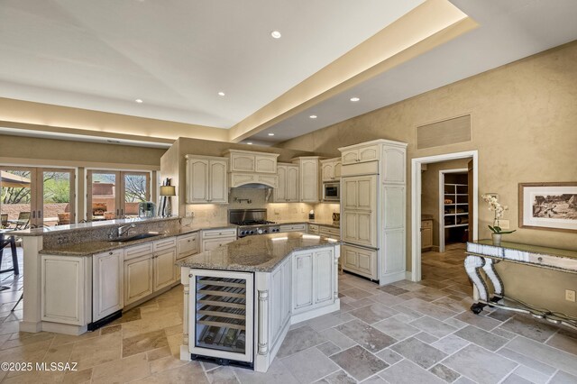 kitchen featuring stainless steel appliances, sink, decorative backsplash, stone countertops, and wine cooler