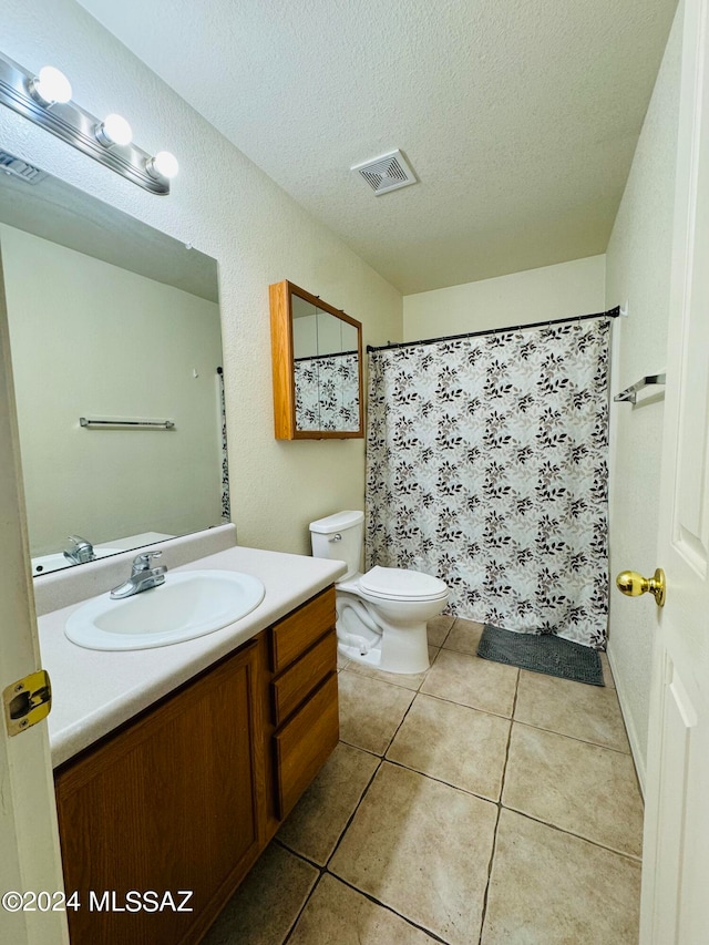 bathroom with toilet, tile patterned flooring, a textured ceiling, and vanity