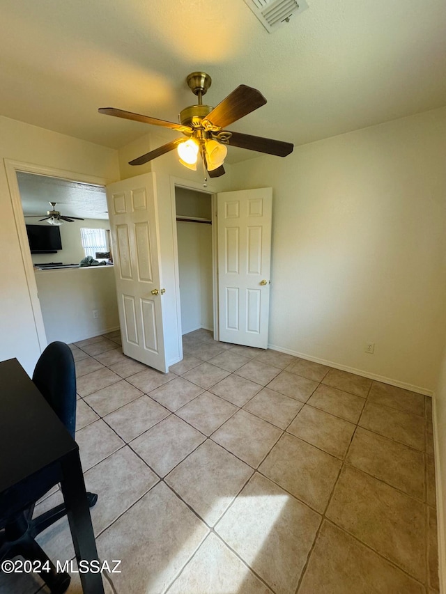 unfurnished bedroom with ceiling fan, light tile patterned floors, and a closet