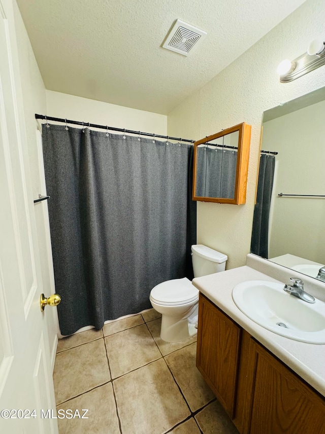 bathroom with tile patterned flooring, a textured ceiling, vanity, and toilet