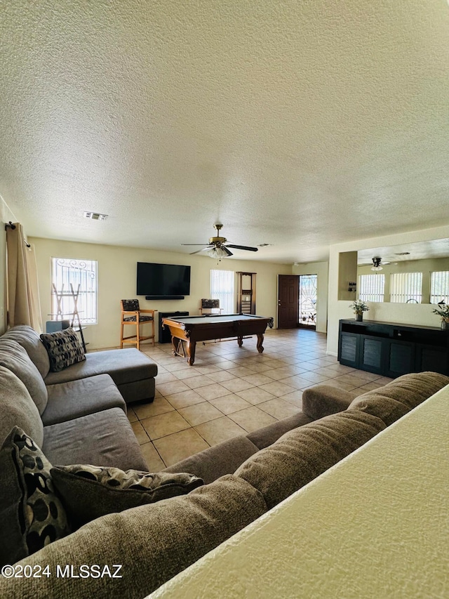 tiled living room featuring a textured ceiling, ceiling fan, and pool table