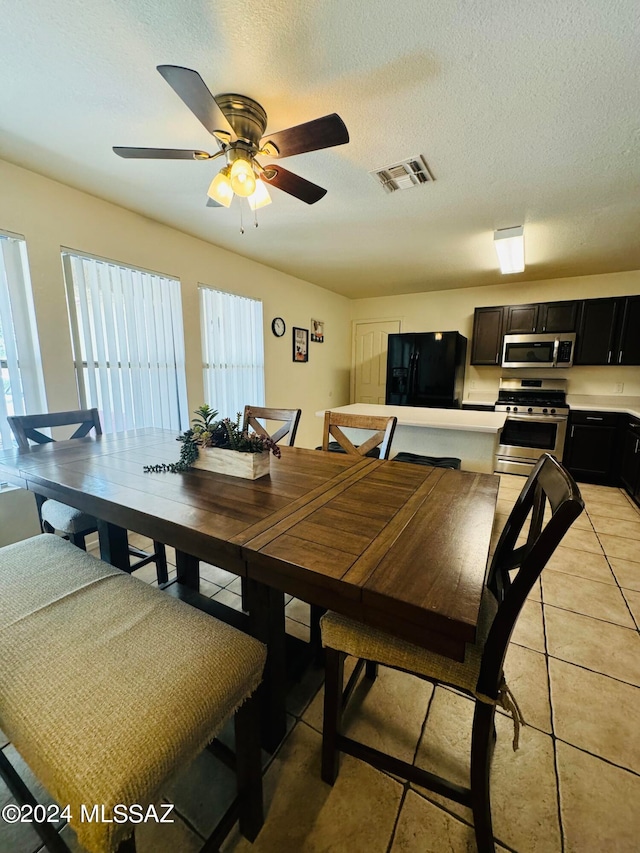 dining area featuring ceiling fan, light tile patterned floors, and a textured ceiling