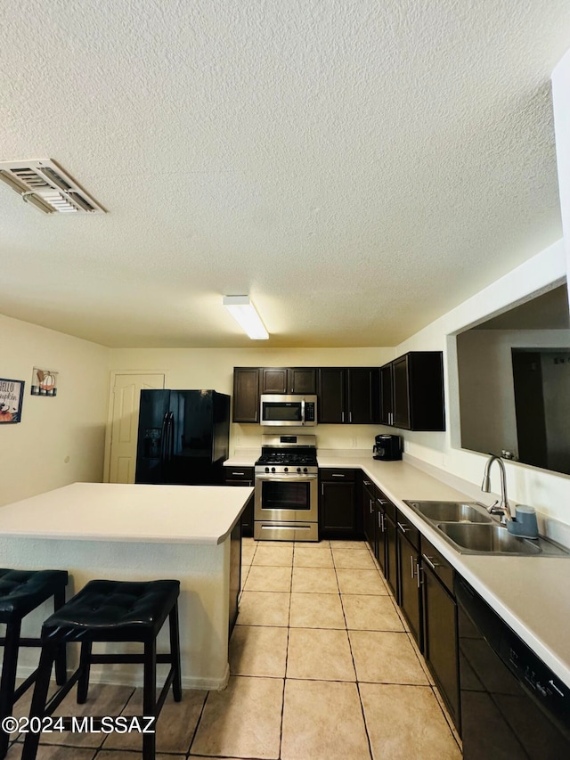 kitchen with a kitchen breakfast bar, light tile patterned floors, sink, a textured ceiling, and black appliances