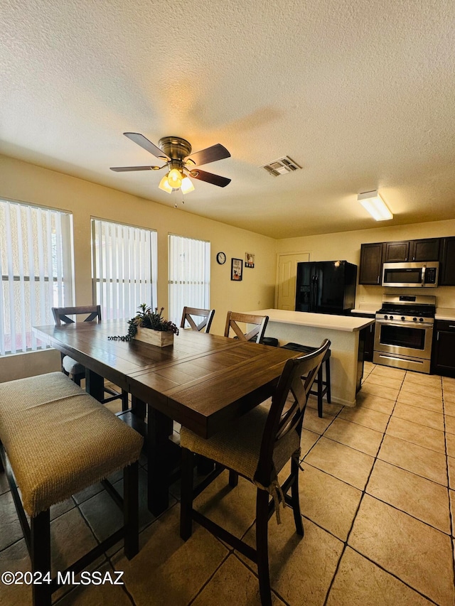 dining area featuring ceiling fan, a textured ceiling, and light tile patterned flooring