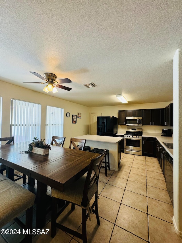 tiled dining area with a textured ceiling and ceiling fan