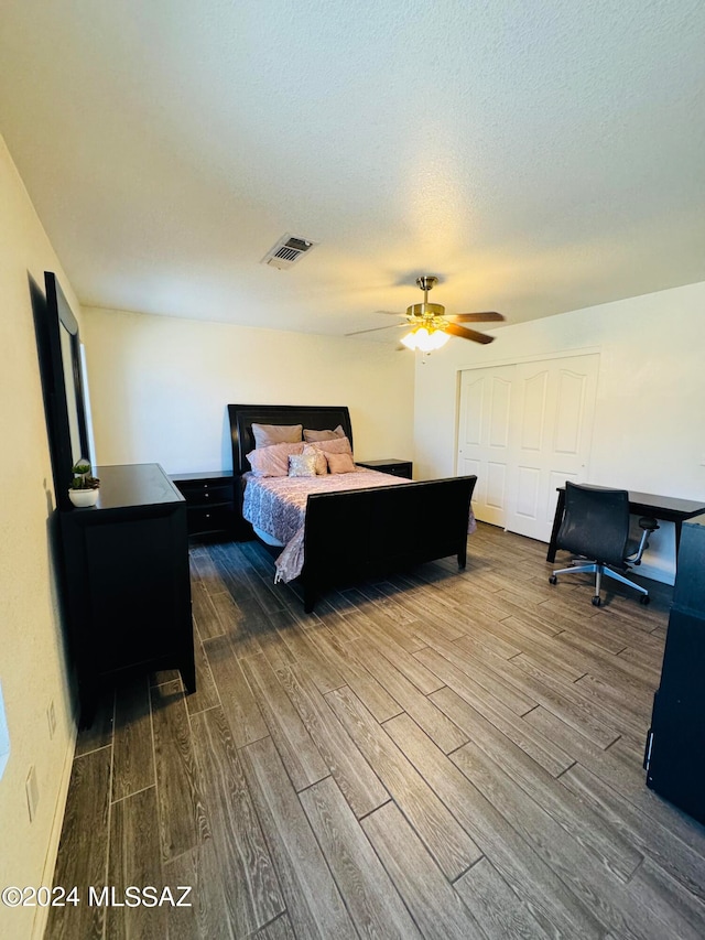 bedroom featuring hardwood / wood-style flooring, a closet, a textured ceiling, and ceiling fan