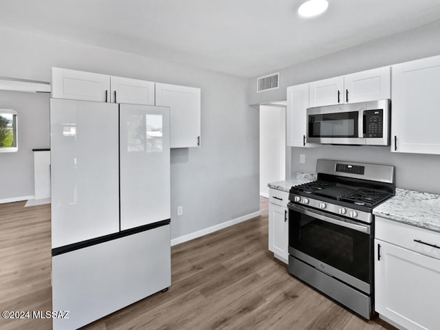 kitchen with white cabinets, light wood-type flooring, and stainless steel appliances