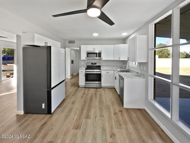 kitchen featuring light hardwood / wood-style floors, a healthy amount of sunlight, white cabinetry, and stainless steel appliances