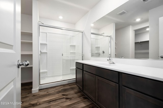 bathroom featuring wood-type flooring, a shower with door, and vanity