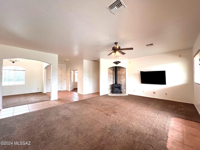 unfurnished living room with tile patterned floors, visible vents, arched walkways, and carpet floors