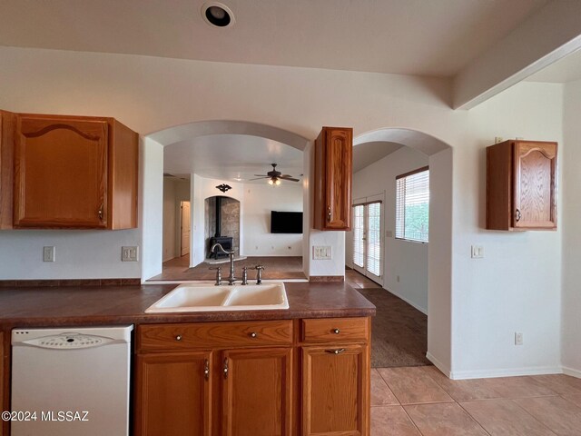 kitchen featuring a sink, dark countertops, arched walkways, and dishwasher