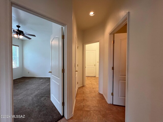 corridor with tile patterned floors, carpet floors, and baseboards