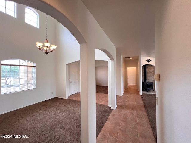 interior space with a notable chandelier, tile patterned flooring, arched walkways, a towering ceiling, and carpet