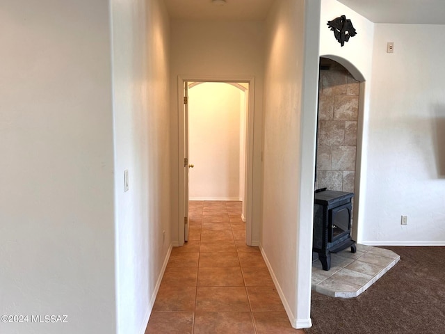 corridor featuring tile patterned floors, arched walkways, and baseboards