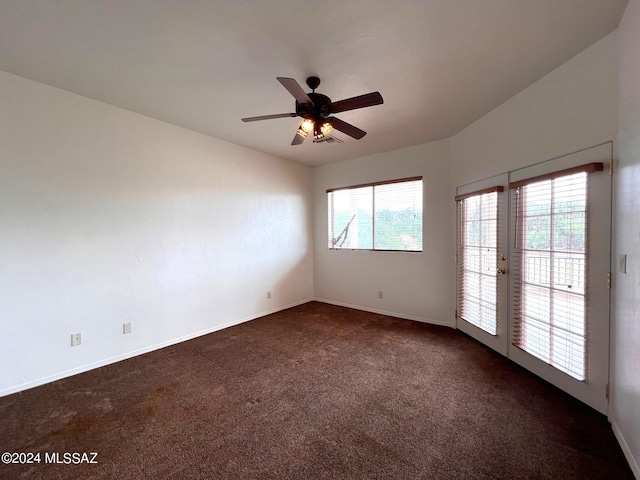 unfurnished room with baseboards, visible vents, a ceiling fan, and dark colored carpet
