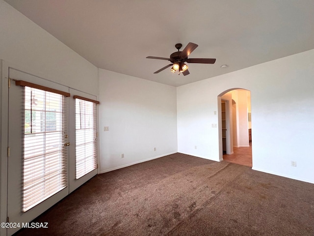 carpeted spare room featuring arched walkways and ceiling fan
