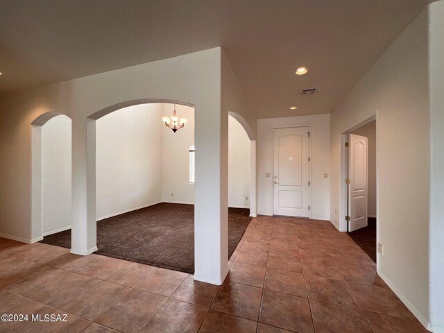 unfurnished room featuring visible vents, recessed lighting, arched walkways, dark tile patterned flooring, and dark carpet