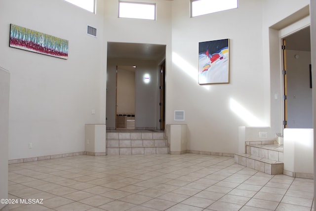 hall with a high ceiling and light tile patterned floors