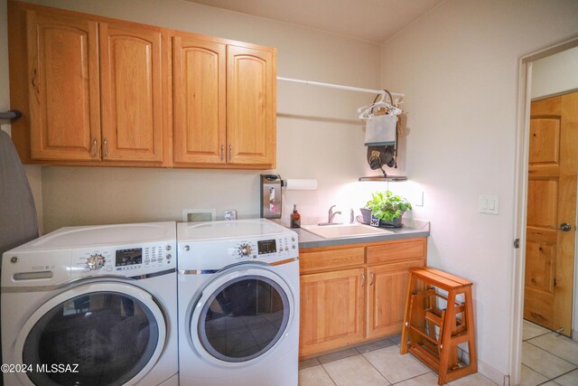 clothes washing area with sink, cabinets, washing machine and clothes dryer, and light tile patterned flooring