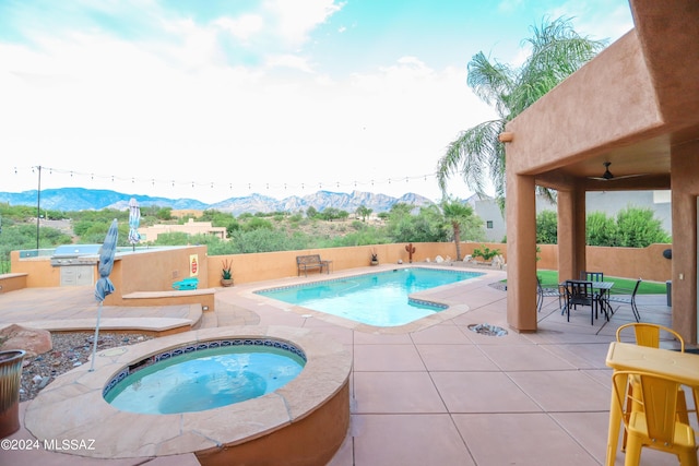 view of pool with exterior kitchen, an in ground hot tub, ceiling fan, a mountain view, and a patio area