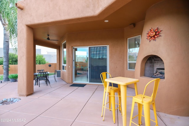 view of patio / terrace with ceiling fan and exterior fireplace