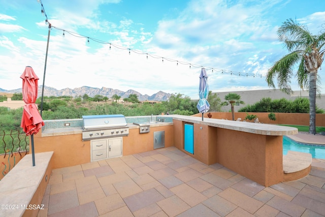 view of patio / terrace with an outdoor kitchen, a mountain view, and area for grilling